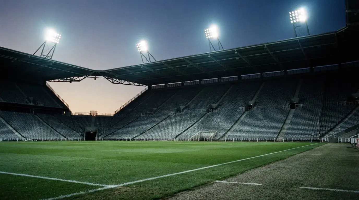 Een leeg voetbalstadion met lichtmasten bij schemering