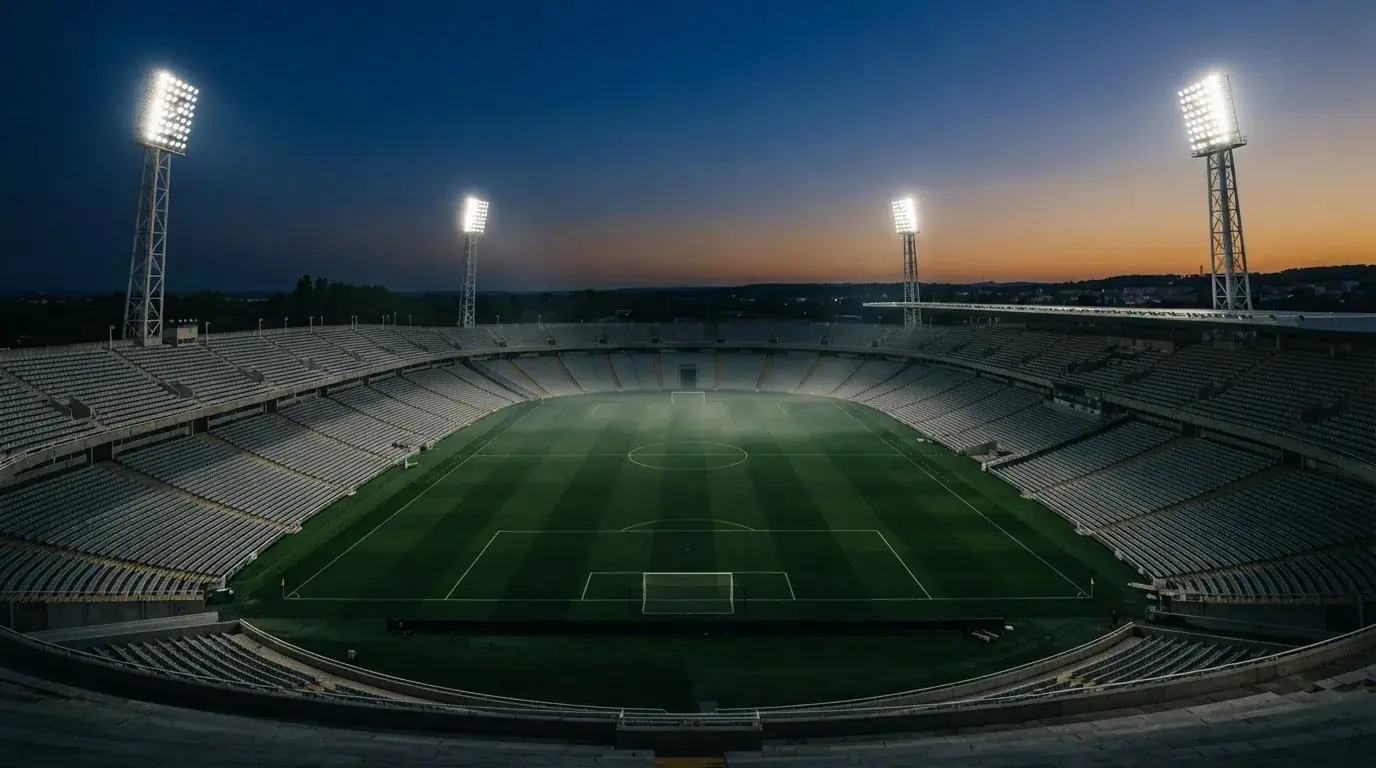 Een leeg voetbalstadion met lichtmasten bij schemering