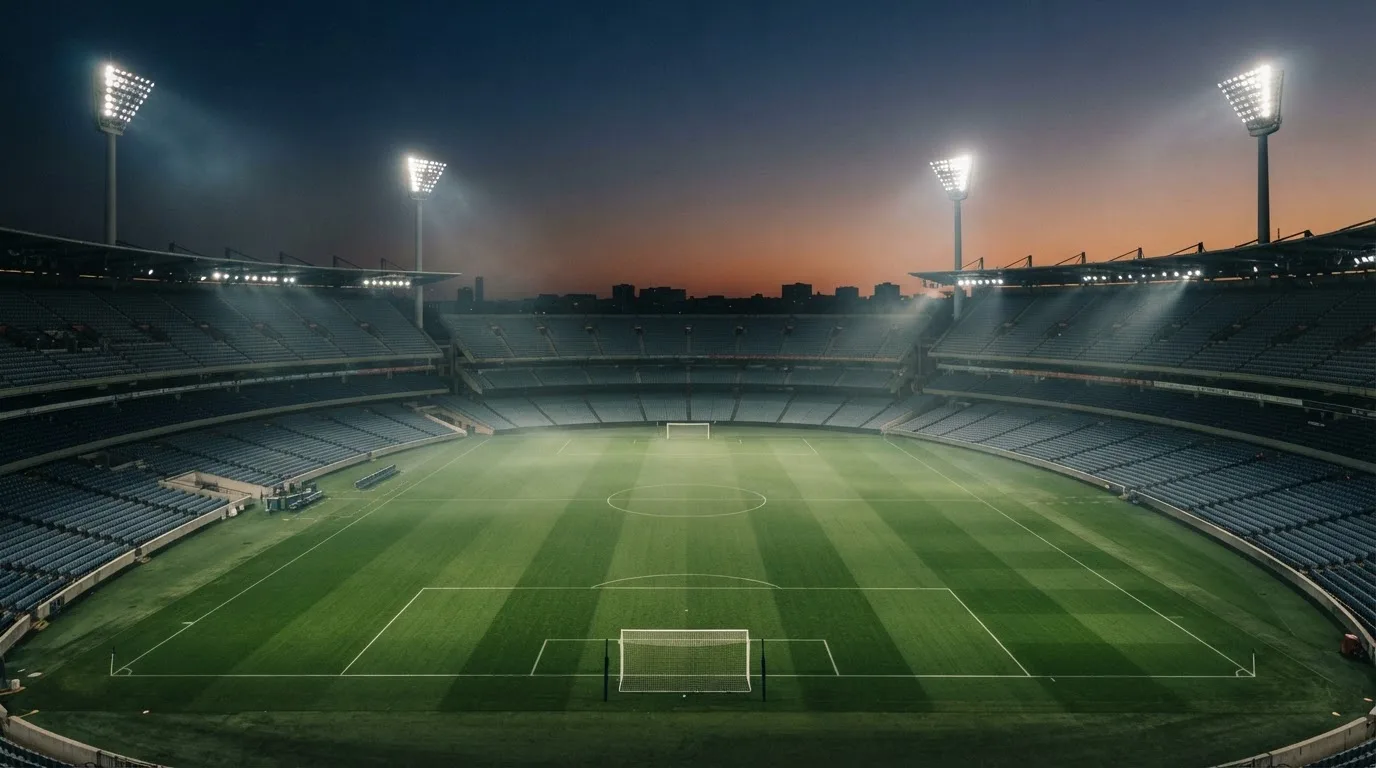 Een leeg voetbalstadion met lichtmasten bij schemering