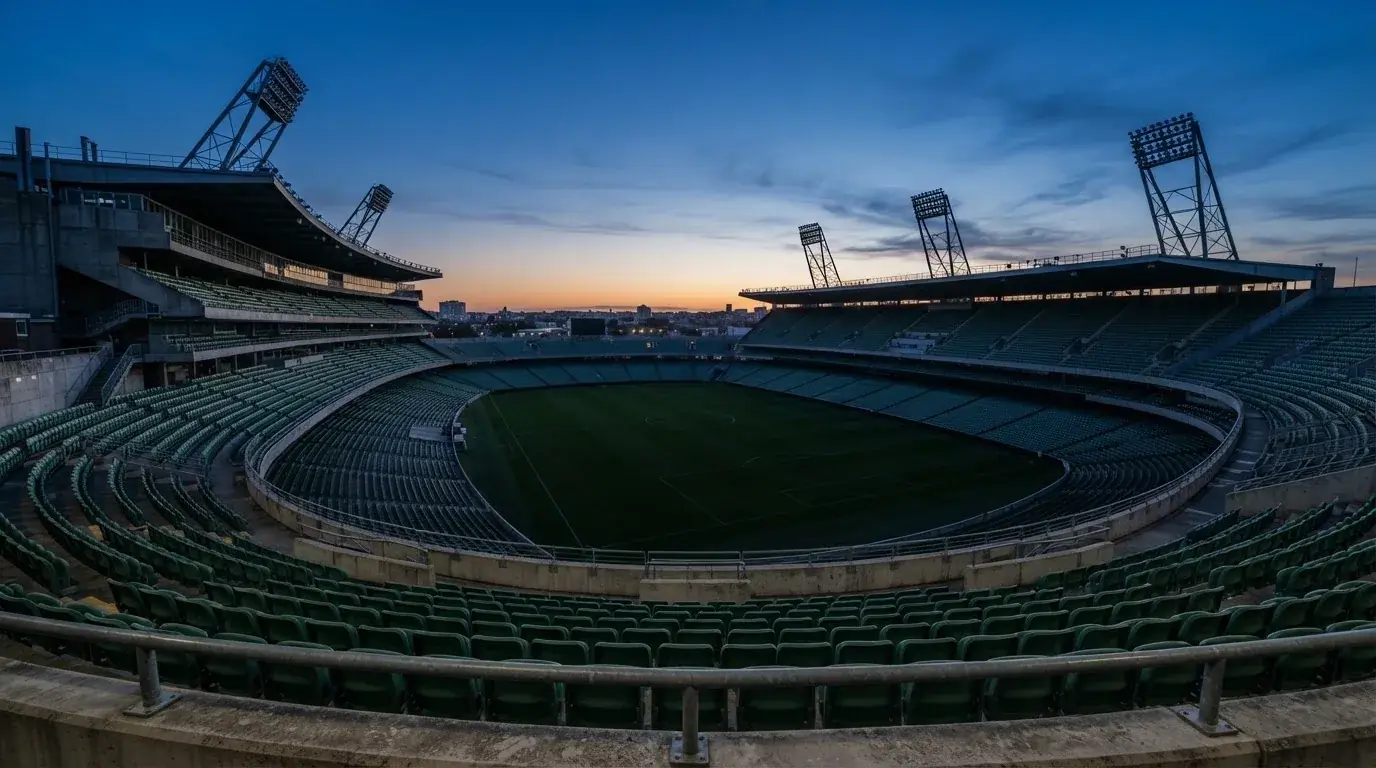 Een leeg voetbalstadion met lichtmasten bij schemering