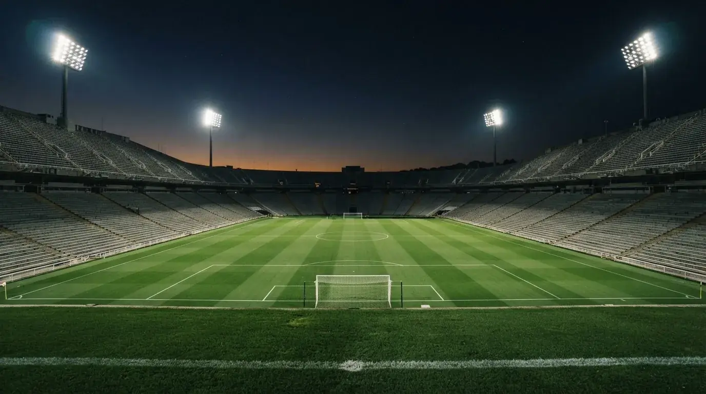 Een leeg voetbalstadion met lichtmasten bij schemering