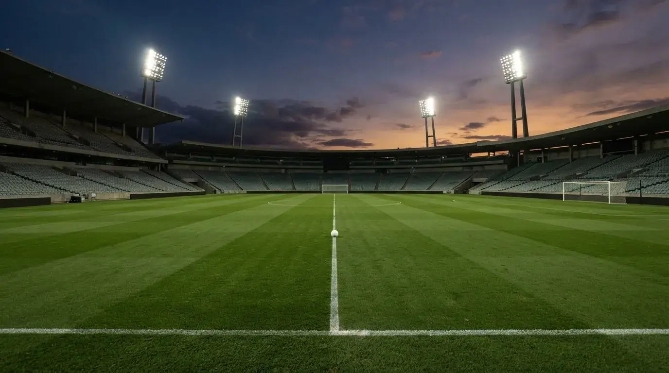 Een leeg voetbalstadion met lichtmasten bij schemering