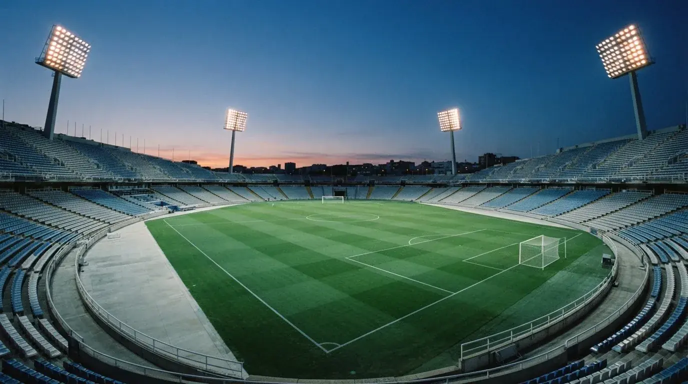Een leeg voetbalstadion met lichtmasten bij schemering