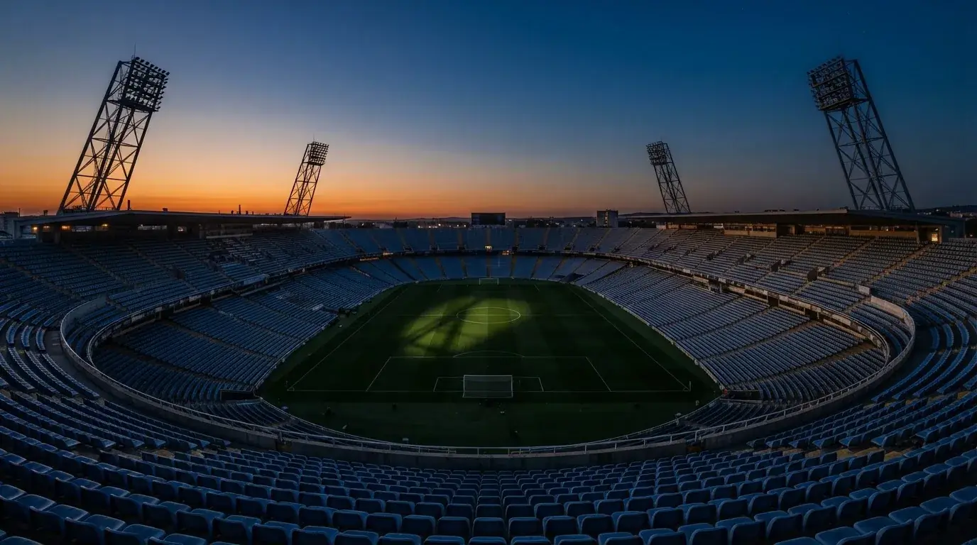 Een leeg voetbalstadion met lichtmasten bij schemering