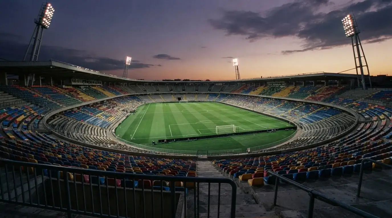 Een leeg voetbalstadion met lichtmasten bij schemering