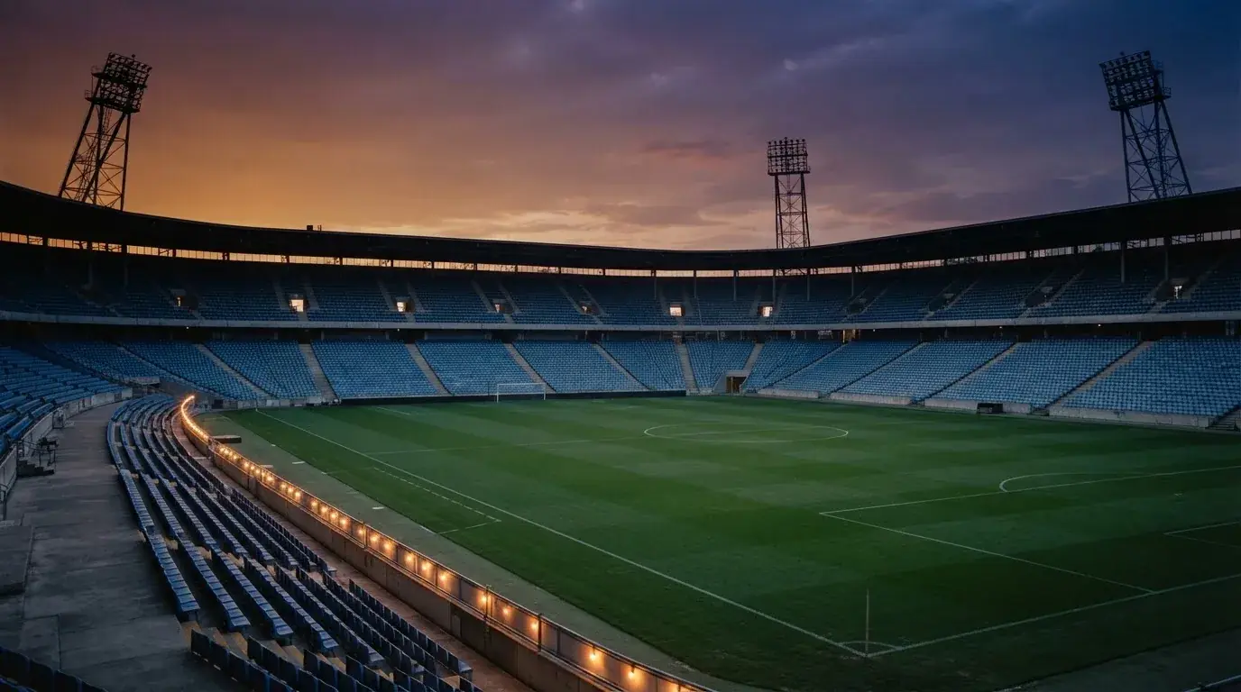 Een leeg voetbalstadion met lichtmasten bij schemering
