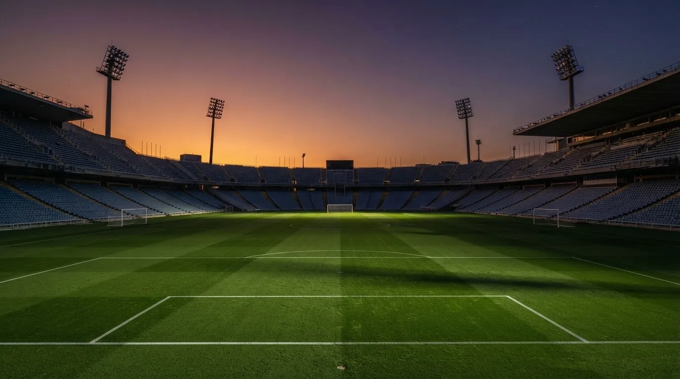 Een leeg voetbalstadion met lichtmasten bij schemering