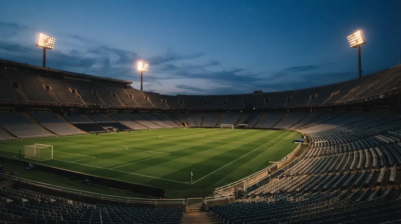 Een leeg voetbalstadion met lichtmasten bij schemering