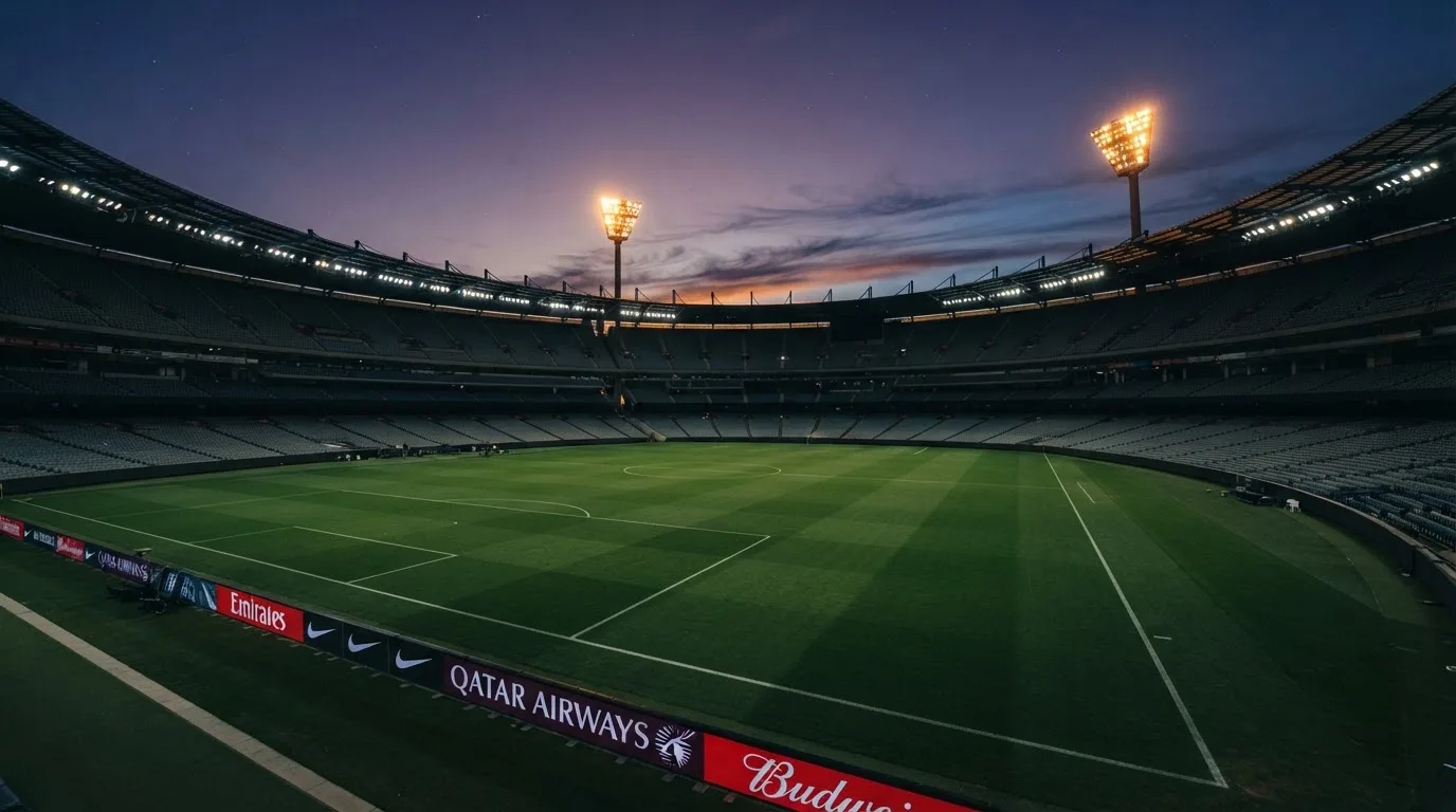Een leeg voetbalstadion met lichtmasten bij schemering